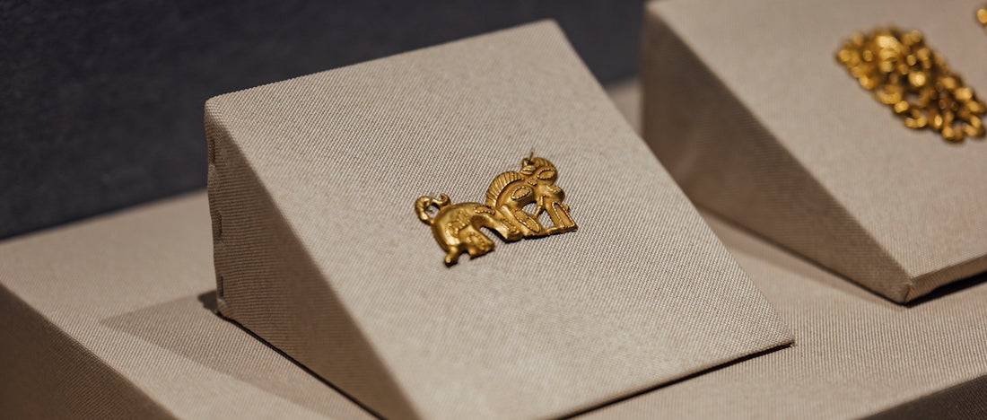 A pair of gold earrings sitting on top of a white box
