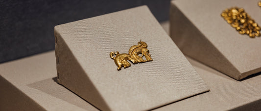 A pair of gold earrings sitting on top of a white box
