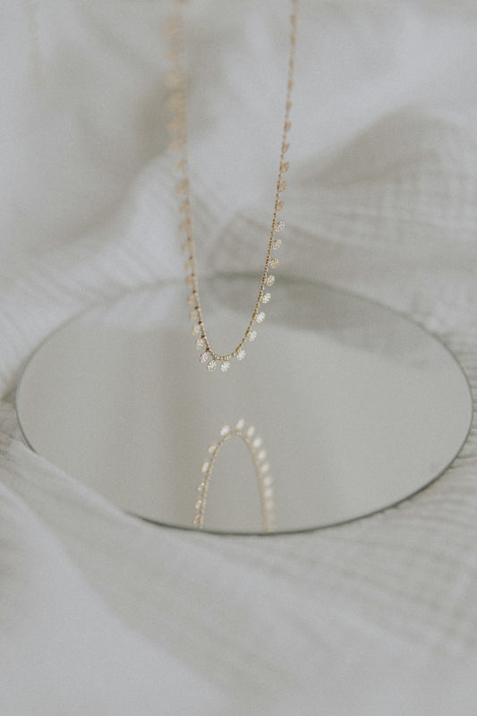 gold necklace on white textile