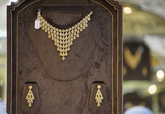a gold necklace and earring set in a display case