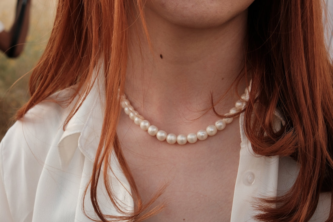 a woman with red hair wearing a pearl necklace