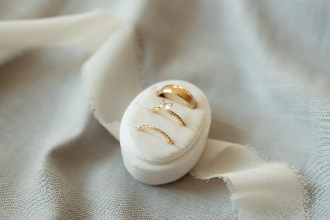 A white ring box with a gold wedding band