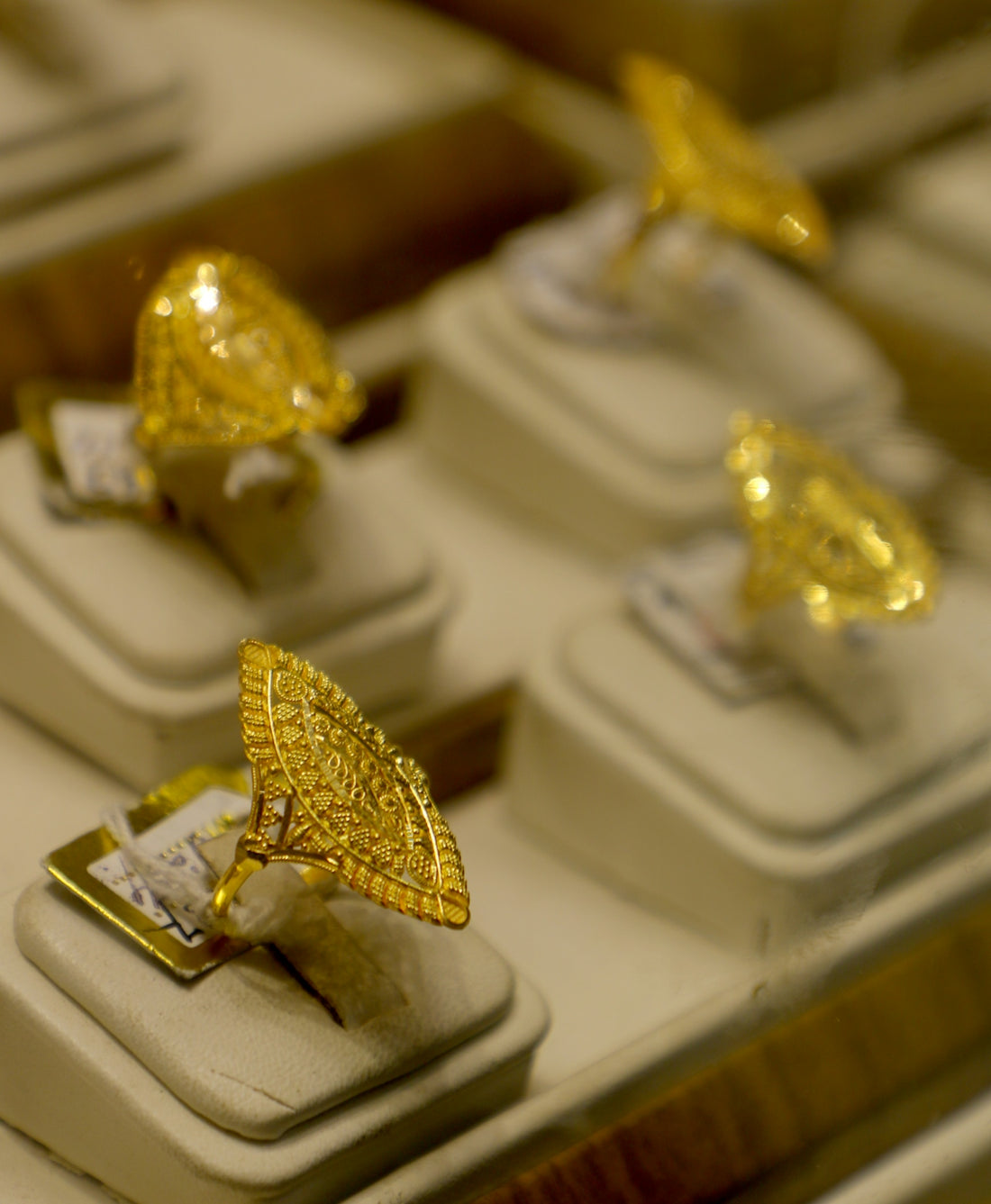 Several ornate gold rings displayed on stands